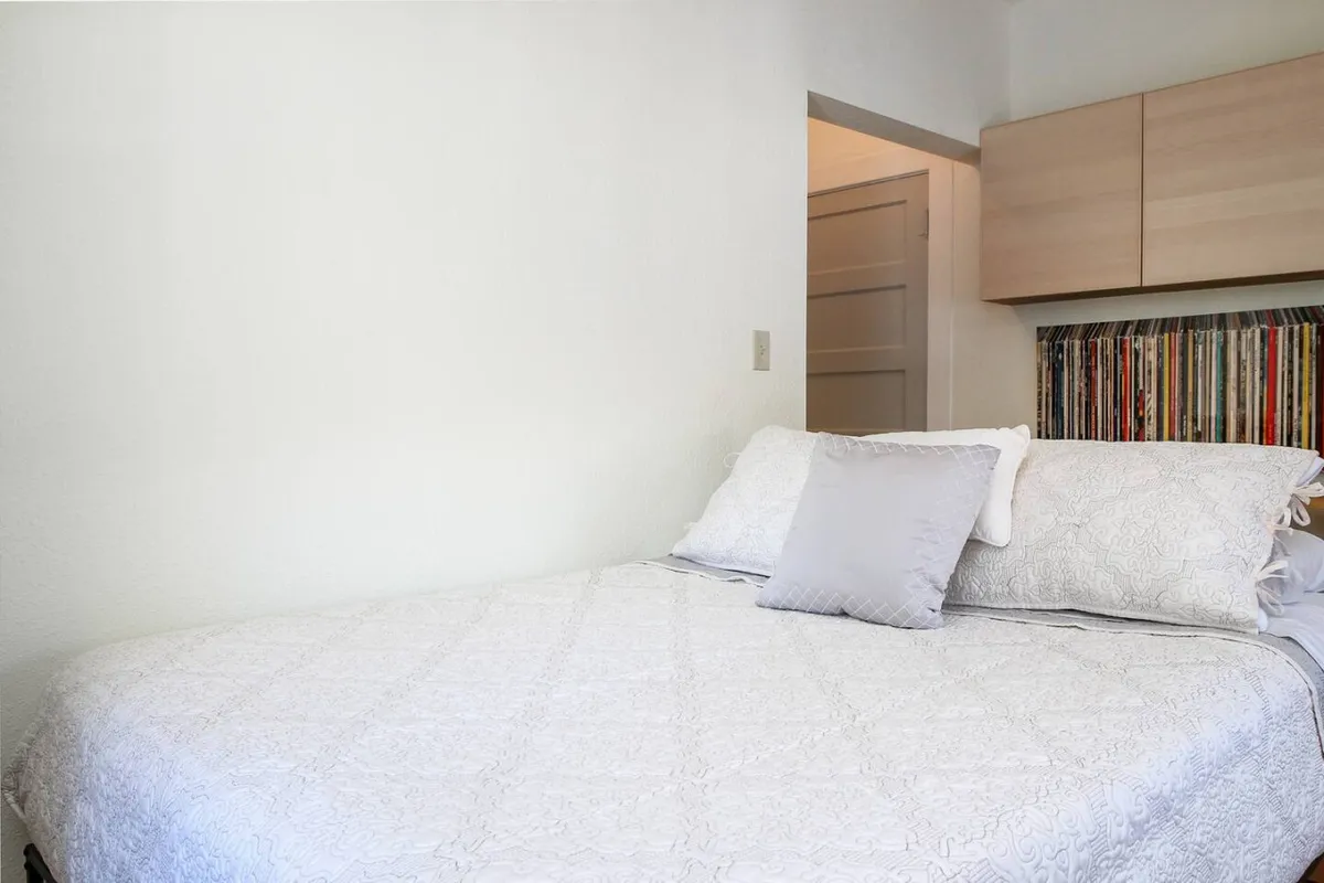 A close-up of a beautifully made bed with a decorative headboard and a plush pillow, set in a peaceful, softly lit environment. The image underscores the comfort and intimacy of the sleeping area.